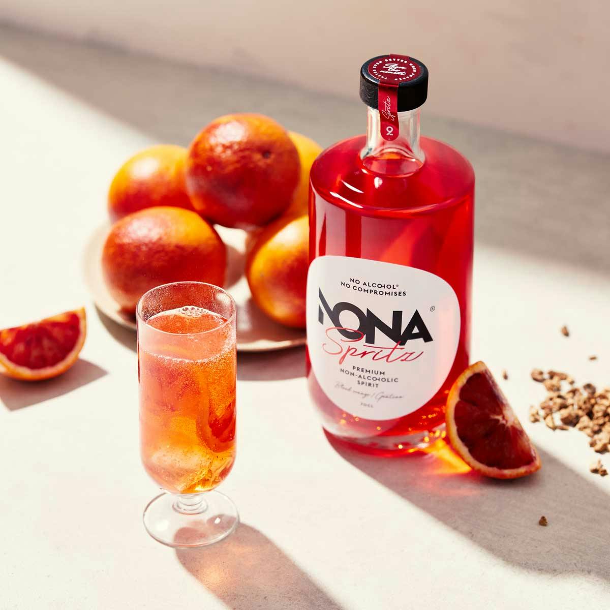 Bottle of non-alcoholic spritz by Nona and glass with non-alcoholic spritz with pomegranets